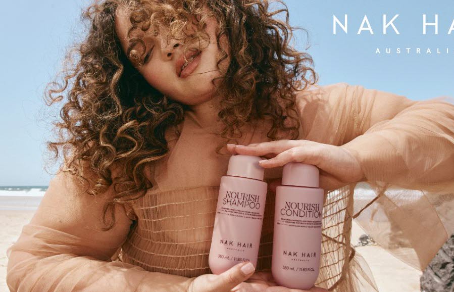 En kvinna som h&aring;ller i produkter fr&aring;n NAK Hair